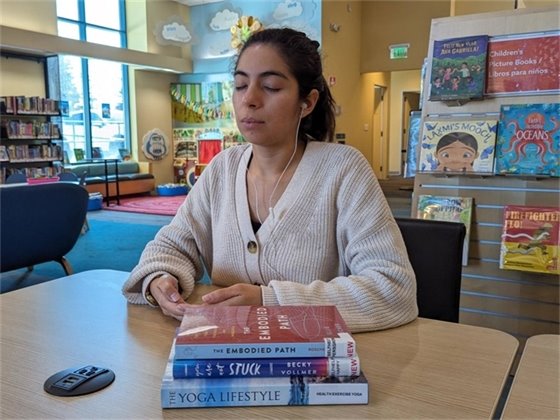 someone sitting in a library meditating listening to calm app
